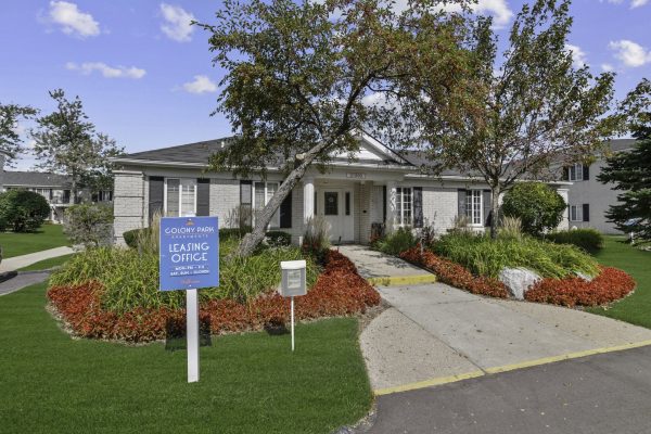 Leasing office exterior with vibrant landscaping at Colony Park Apartments on a sunny day.