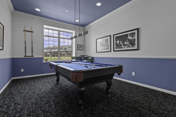 Billiard room with blue pool table, cues on the wall, large window, and stylish décor in a modern setting.