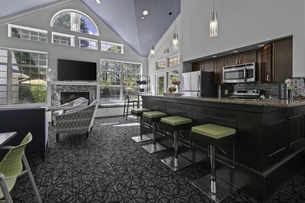 Modern living room with vaulted ceilings, large windows, kitchen bar, stools, and stylish seating.