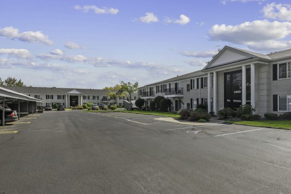 Expansive residential apartment complex with parking lot under a clear blue sky.