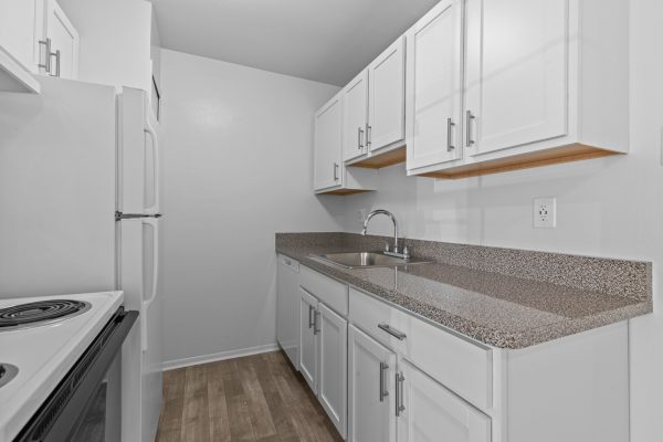 Modern kitchen with white cabinets, granite countertops, stainless steel sink, and wood floors.