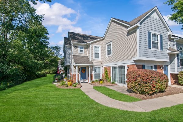 Suburban house with landscaped yard, bright blue sky, and autumn decorations on door.