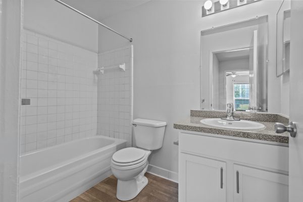 Modern bathroom with white tiles, bathtub, toilet, and granite countertop sink for a clean, sleek design.