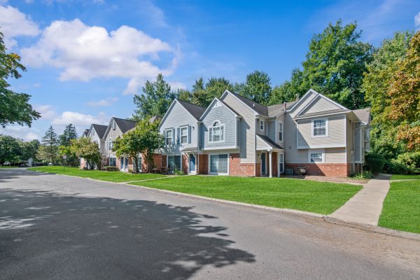 Suburban residential homes with lush greenery on a sunny day, showcasing modern architecture and peaceful surroundings.