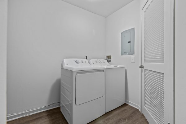 Minimalist laundry room with white washer and dryer on wood floor.