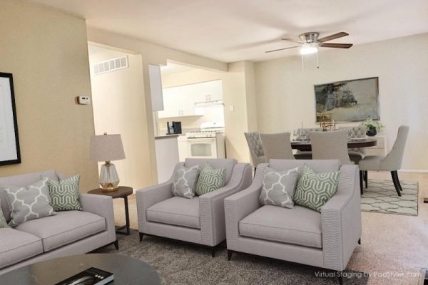 Modern living room with gray sofas, green pillows, dining area, and kitchen in open layout. Cozy and stylish decor.