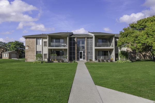 Modern apartment building with balconies and a lawn on a sunny day.