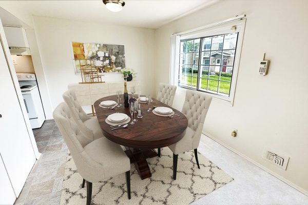 Elegant dining room with wooden table, cushioned chairs, and window view, set for a formal meal.