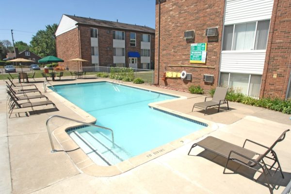 Outdoor apartment swimming pool with lounge chairs and umbrellas on a sunny day.