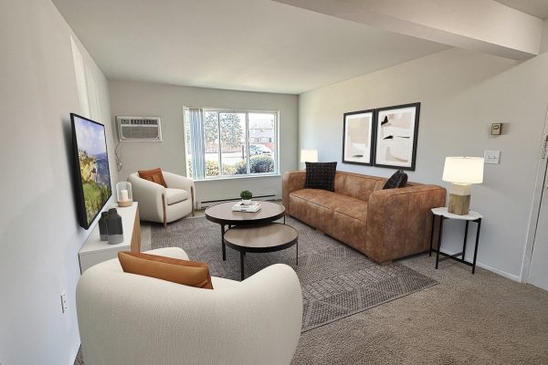 Modern living room with brown sofa, white chairs, TV, round coffee tables, and large window. Cozy and stylish decor.