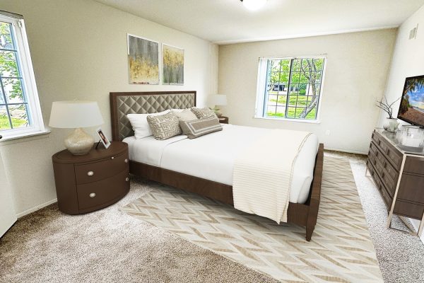 Cozy bedroom with brown furniture, plush carpeting, and decorative pillows; natural light from windows enhances the space.