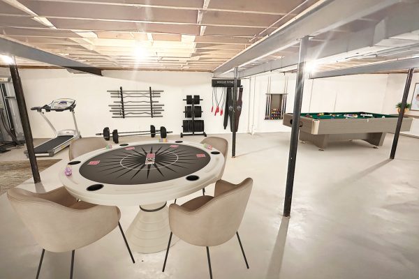 Basement recreation room with poker table, gym equipment, and pool table for entertainment and fitness.