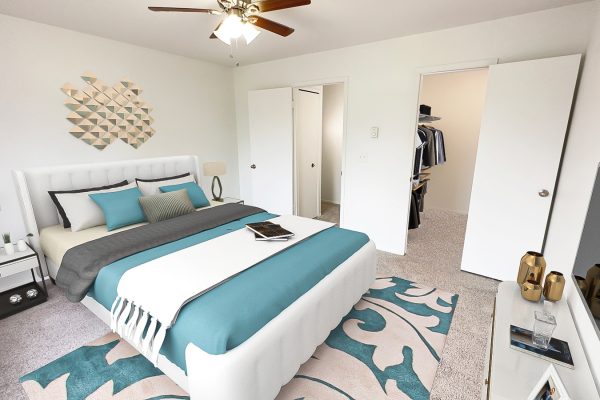 Modern bedroom with teal accents, stylish geometric wall art, and a cozy bed. Spacious walk-in closet visible.