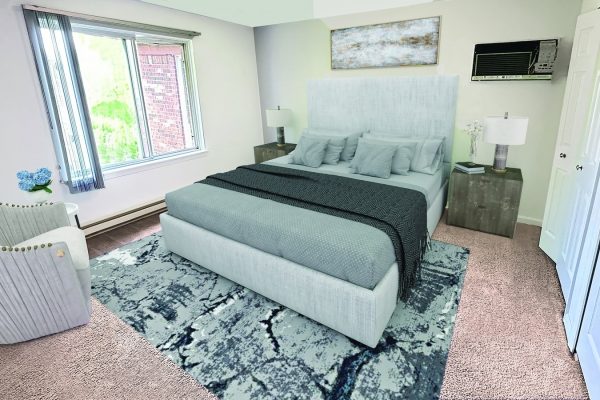 Modern bedroom with cozy gray bed, elegant decor, large window, gray armchair, and abstract rug.