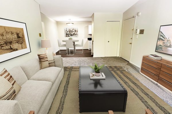 Modern living room with beige sofa, black coffee table, wall art, and TV. Open dining area with table and chairs.