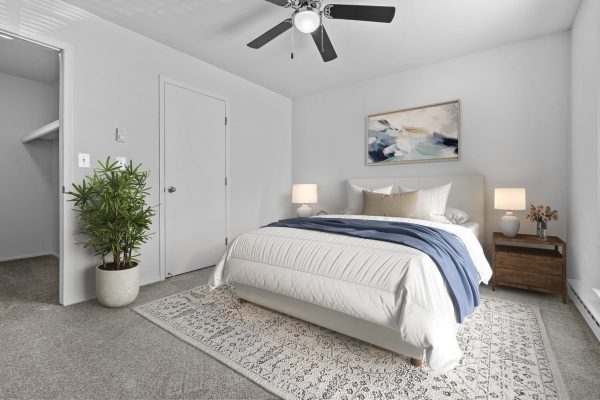 Modern bedroom with white bedding, blue accent, abstract art, and houseplant for a serene atmosphere.