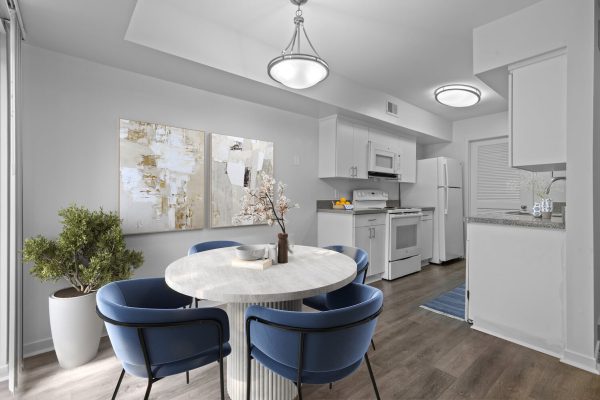 Modern kitchen and dining area with blue chairs, abstract art, and stainless appliances.