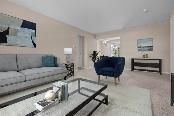 Modern living room with gray sofa, blue armchair, glass coffee table, and decor accents.