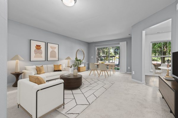 Modern living room with neutral decor, featuring a cozy sofa, coffee table, and dining area with large windows.