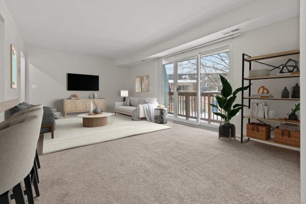 Modern living room with cozy sofa, coffee table, TV, and large windows overlooking a balcony with natural light.
