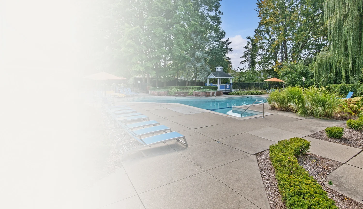 Outdoor pool area with lounge chairs, surrounded by lush greenery; perfect for relaxation and leisure activities.