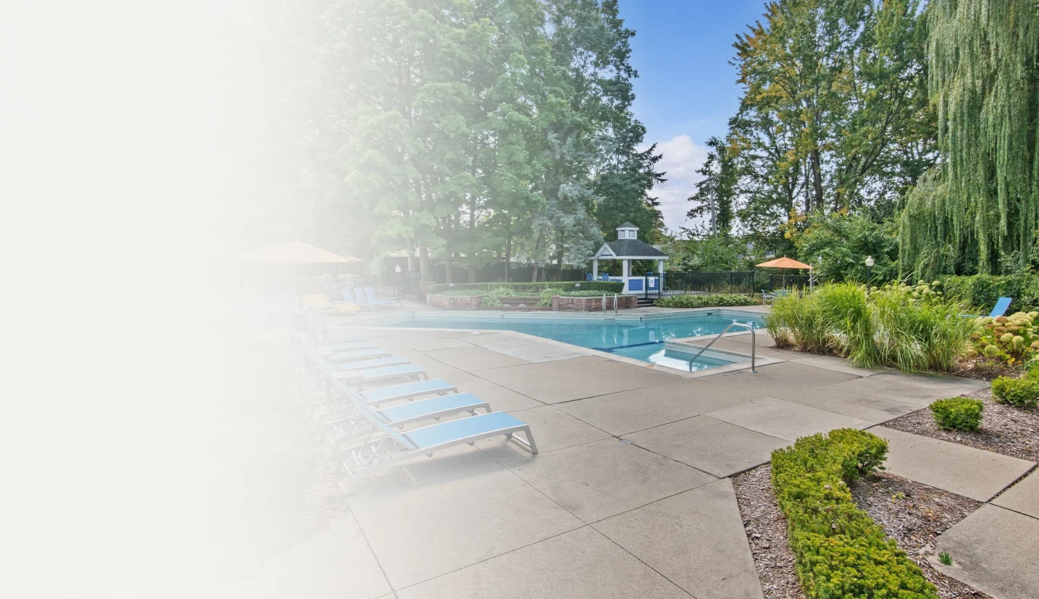 Outdoor pool with lounge chairs and umbrellas surrounded by lush greenery, perfect for relaxation.